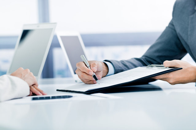 verweist auf: Informationspflichten (Quelle: ©Nonwarit - stock.adobe.com) eine Hand mit Kugelschreiber zeigt auf ein Papier und gegenüber sind zwei Hände übereinandergelegt (verweist auf: Informationspflichten)