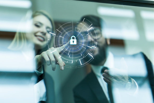 verweist auf: Datenschutz in der Arbeitsverwaltung (Quelle: guvendemir via Getty Images) in der Mitte einer milchigen Glasfläche ist ein digitales Schlosssymbol und dahinter stehen zwei Personen (verweist auf: Datenschutz in der Arbeitsverwaltung)