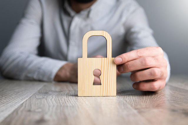 verweist auf: Die Grundlagen des Datenschutzrechts (Quelle: ©Tiko - stock.adobe.com) ein Schloss in Holzoptik wird von einer Hand gehalten (verweist auf: Die Grundlagen des Datenschutzrechts)