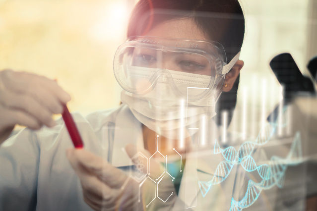 es ist eine Frau in einem Labor mit Brille und Reagenzglas in der Hand abgebildet (verweist auf: Medizinische Forschung mit Gesundheitsdaten)