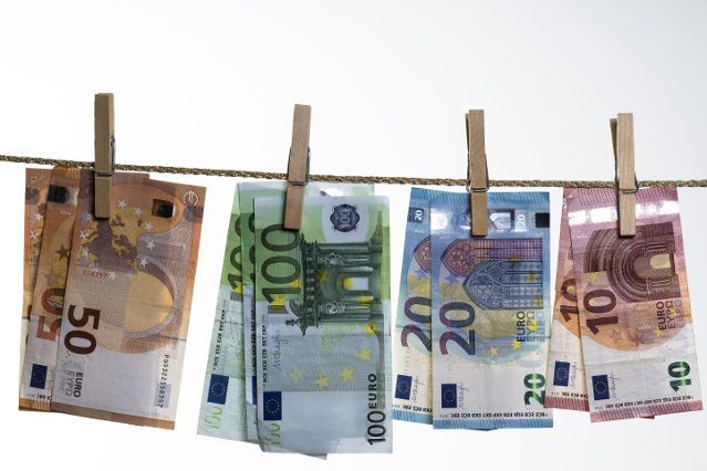 verschiedene Geldscheine sind mit einer Wäscheklammer auf einer Leine aufgehängt (verweist auf: Zentralstelle für Finanztransaktionsuntersuchungen - FIU)