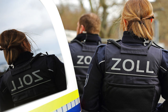 verweist auf: Zollfahndungsdienst (Quelle: ©Andreas Scholz - stock.adobe.com) zwei Zollbeamte von hinten und auf der Rückansicht der Dienstkleidung ist die Aufschrift Zoll zu lesen (verweist auf: Zollfahndungsdienst)