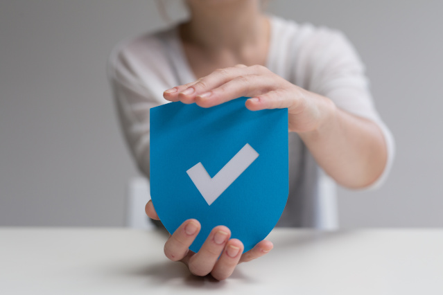 a shield with a hook in the middle is held by two hands below and above (Source: ©vegefox.com - stock.adobe.com) a shield with a hook in the middle is held by two hands below and above